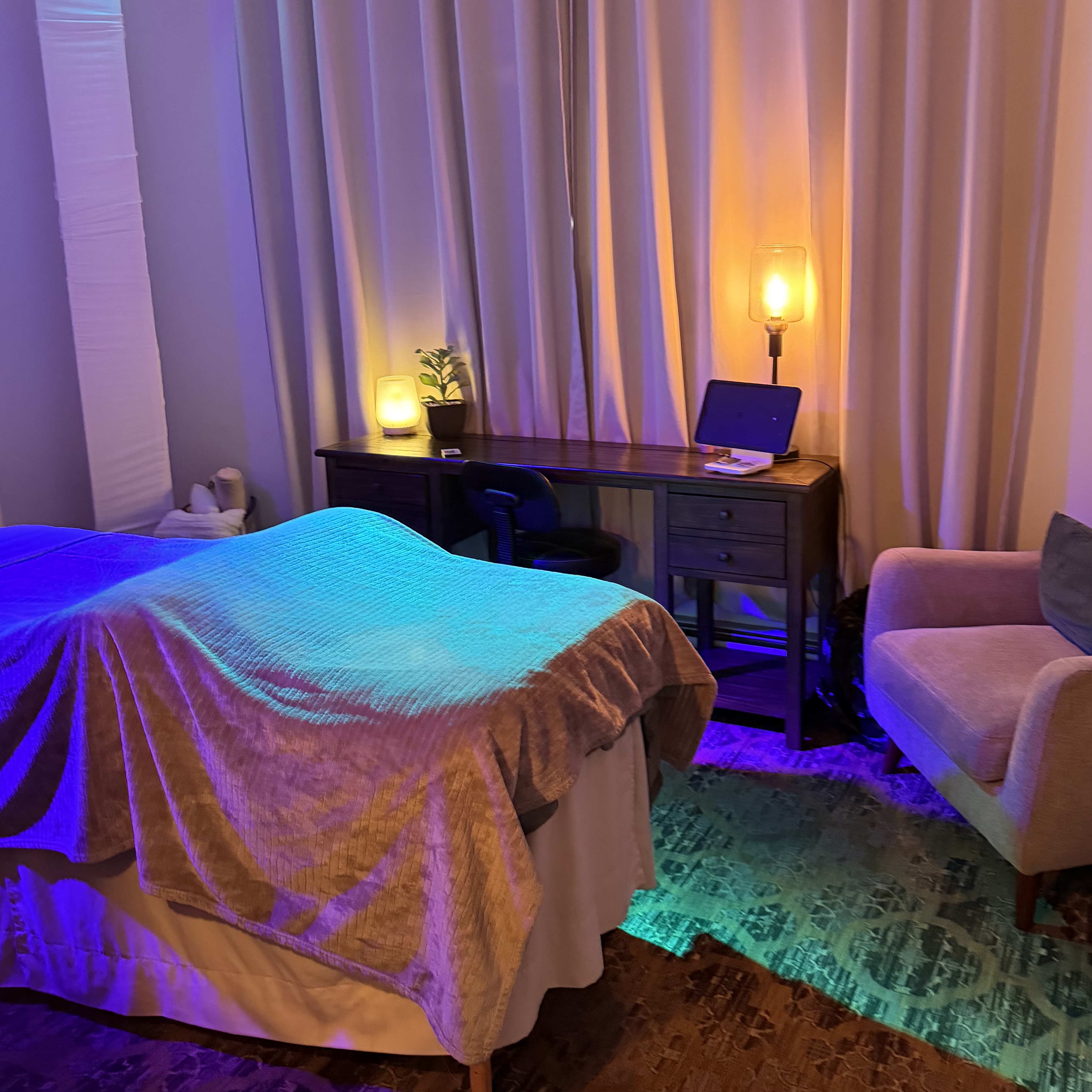 Candlelit massage studio with amber and teal lighting